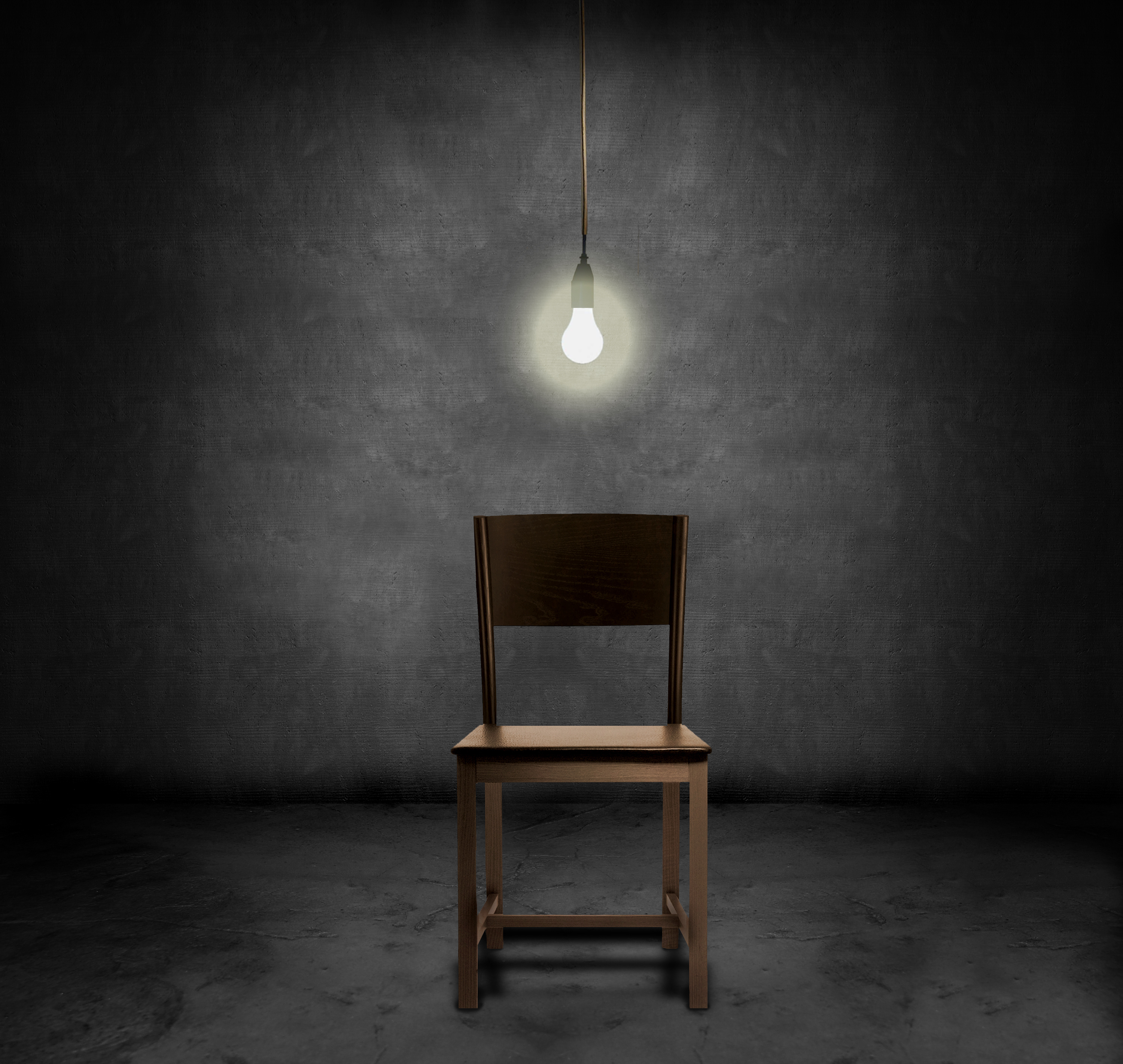 An empty chair and hannging light bulb in a dark room